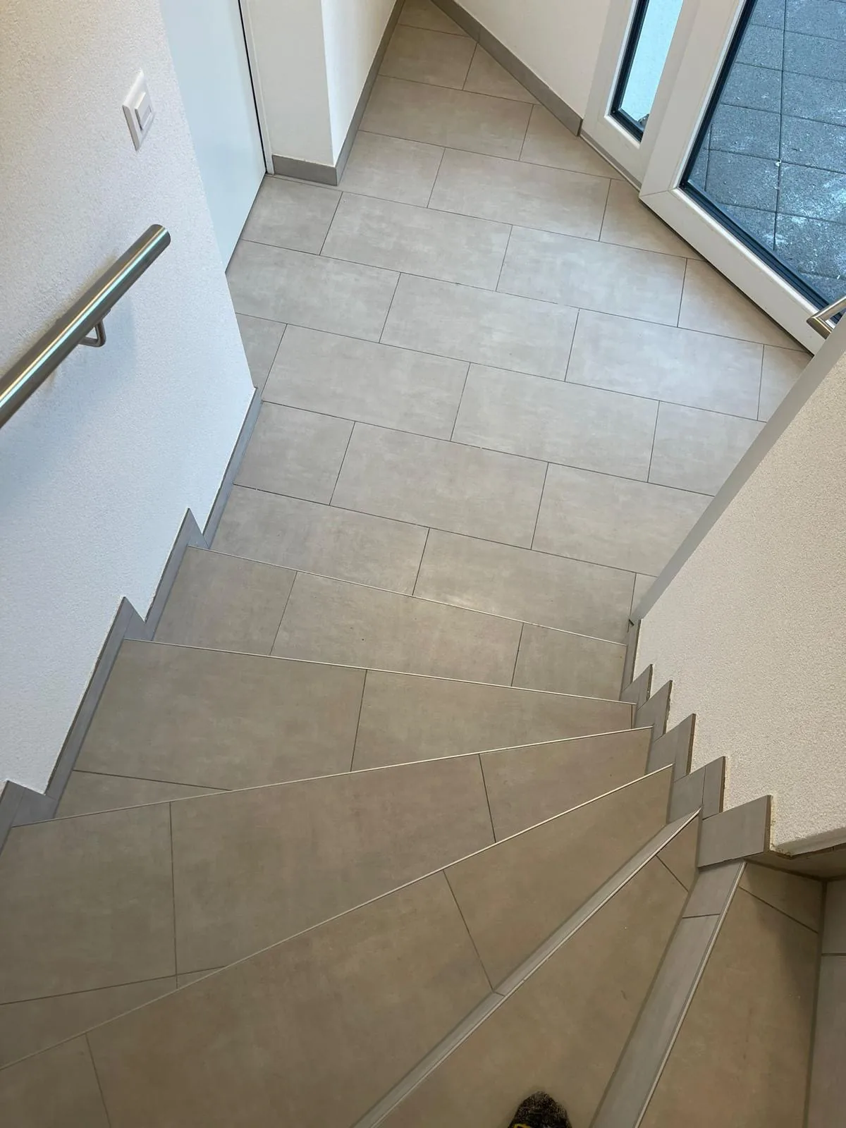 Escalier carrelé terminé avec murs blancs et main courante