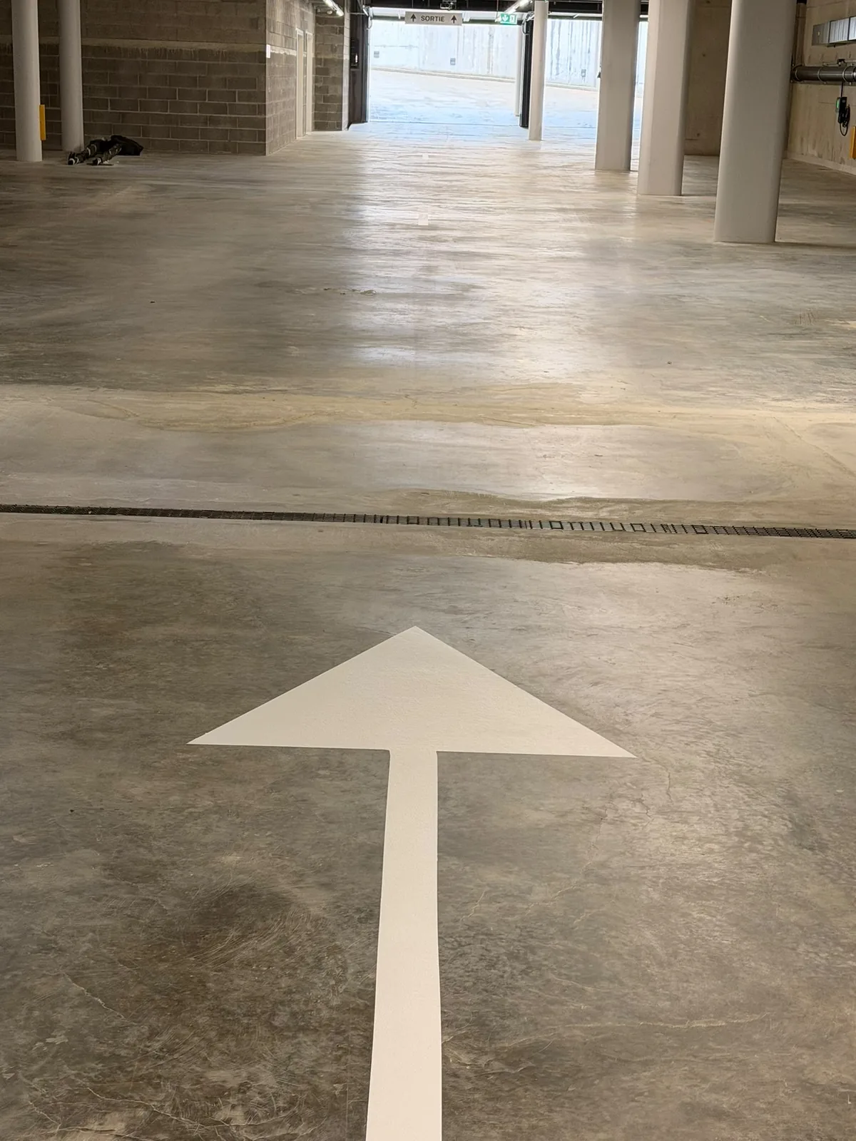 Flèche directionnelle blanche peinte sur une dalle de béton