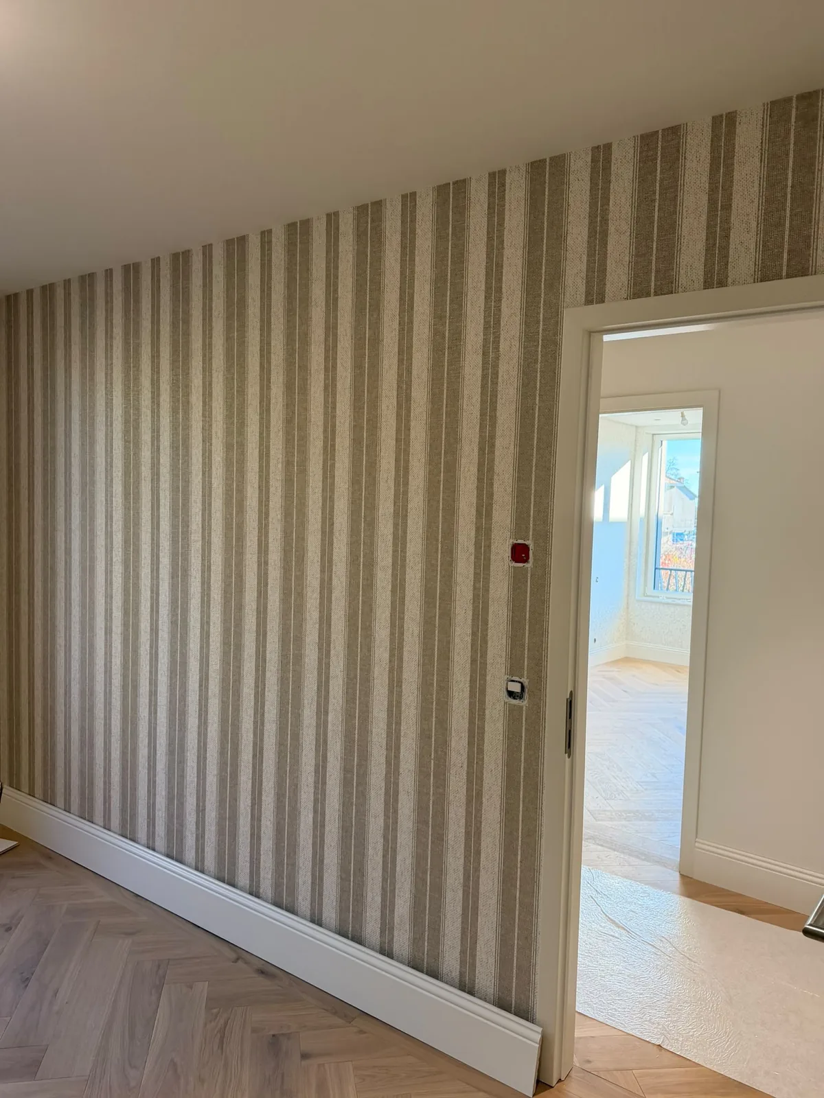 Papier peint à rayures beiges dans un couloir avec parquet en chevrons