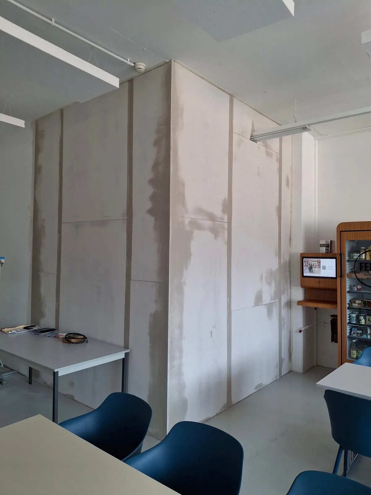Grande cloison lissée dans une salle commune meublée
