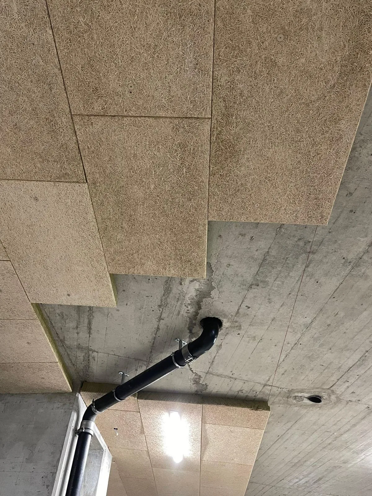 Panneaux de fibre isolante fixés sous une dalle de parking