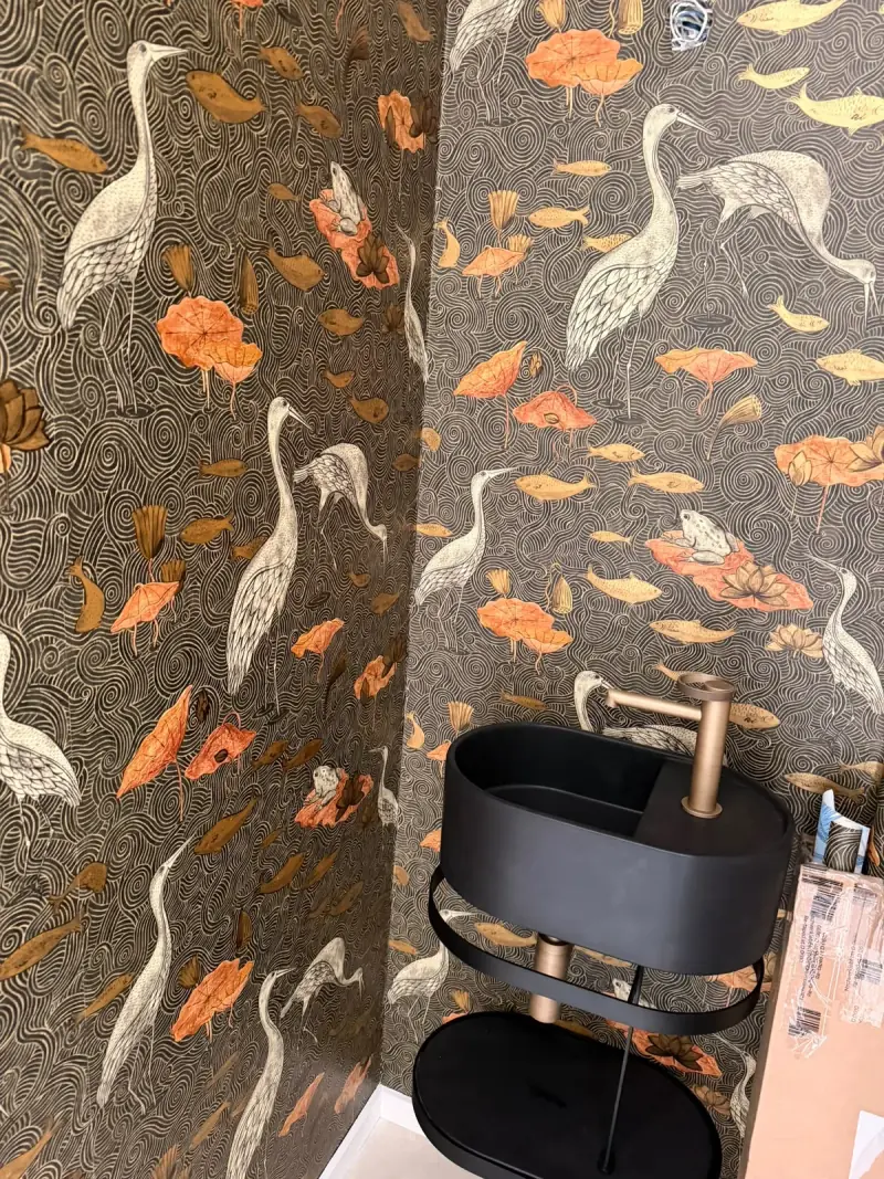 Papier peint à motifs de hérons et nénuphars derrière une vasque noire