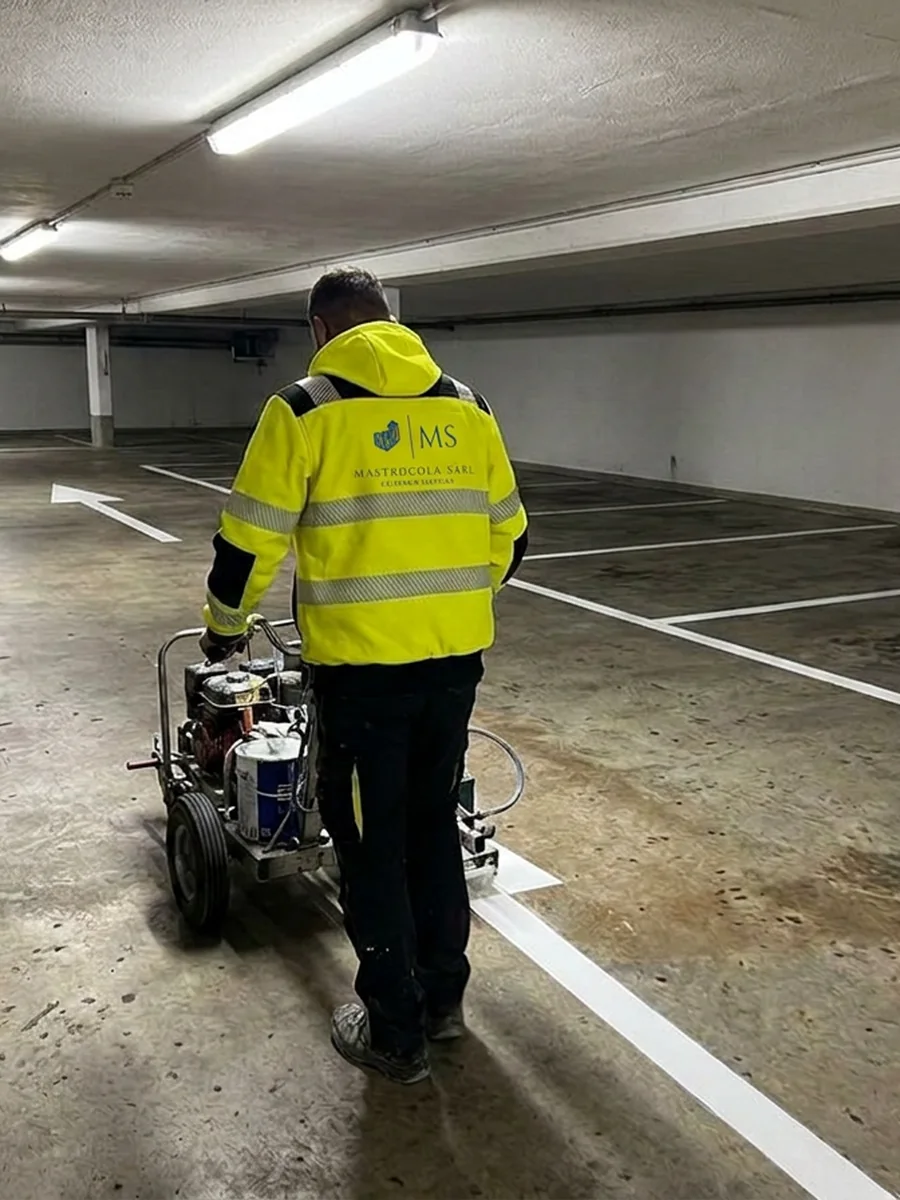 Artisan Mastrocola traçant les lignes d'un parking souterrain à la machine